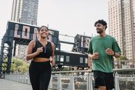 Man in Green Crew Neck T-shirt and Black Pants Standing Beside Woman in Black Sports