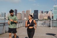 Woman in Black Sports Bra and Black Leggings Standing on Brown Wooden Dock