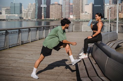 Free A couple enjoying a workout session on a wooden deck by a city waterfront, embracing a healthy lifestyle. Stock Photo