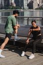 一对夫妇在户外锻炼时停了下来，一个在看手表，另一个在伸展身体