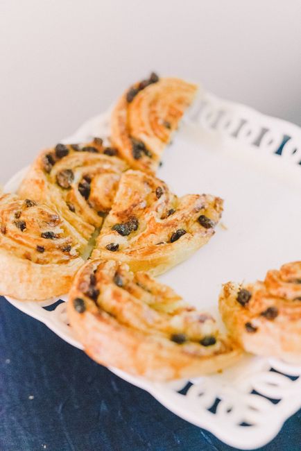 A baking sheet of golden-brown puff pastry pinwheels with visible cinnamon-sugar spirals, cooling on parchment paper.