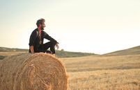 Man in Black Jacket Standing on Brown Grass Field