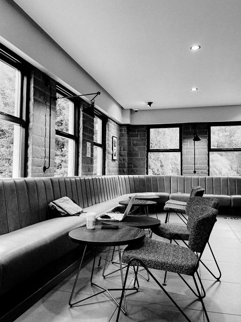 Black and white of comfortable cafe with soft furniture and wooden table with laptop and cup of coffee