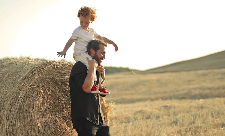 Father Giving Son Piggyback Ride In Field