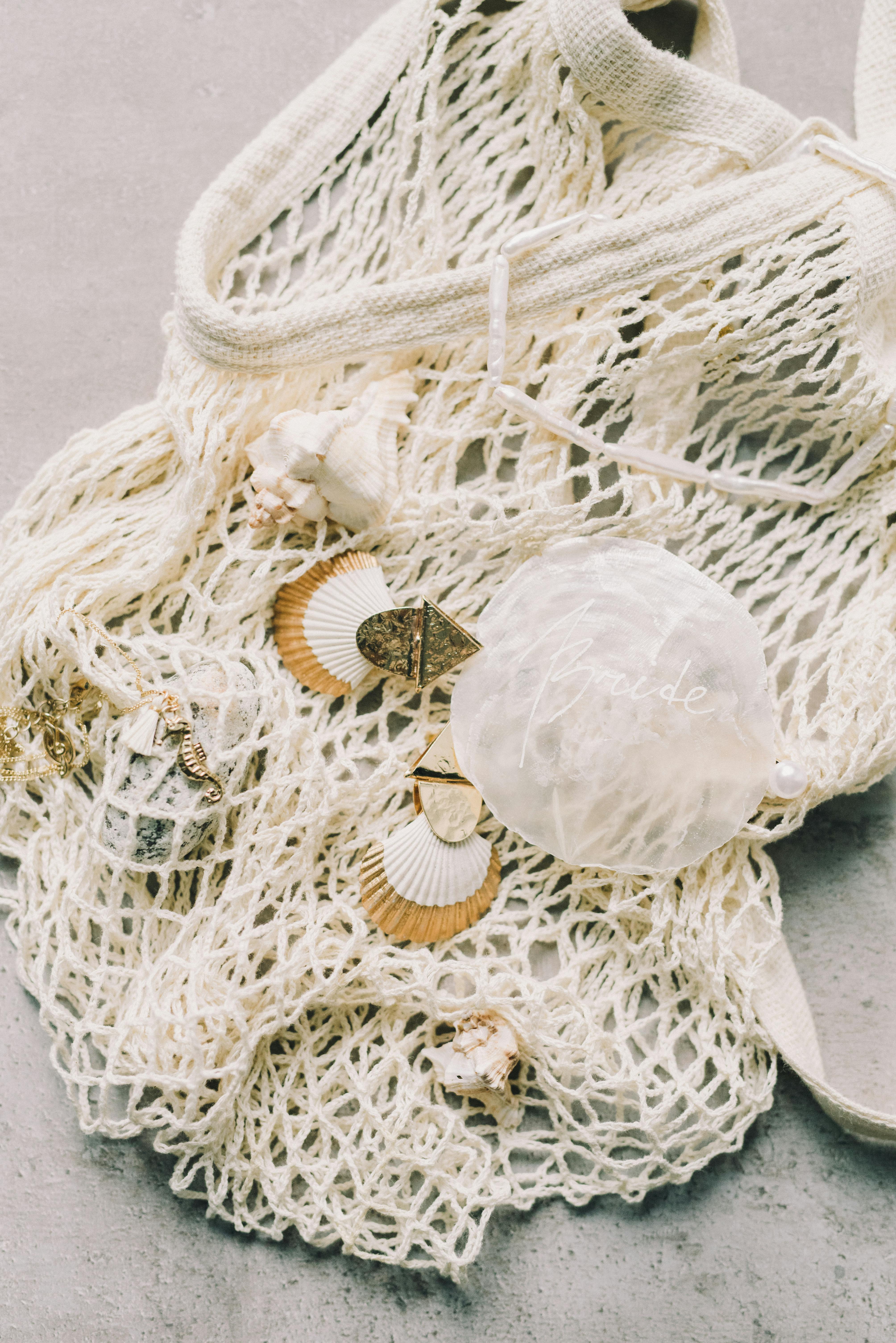 白色针织棉袋搭配装饰性贝壳，背景柔和