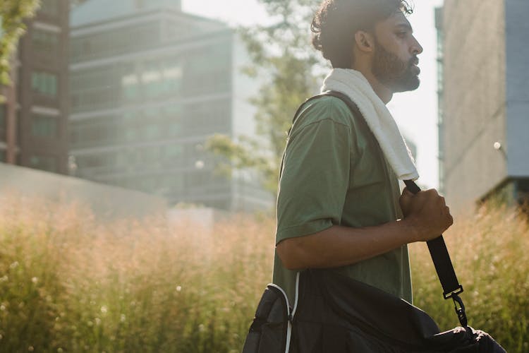 A Man In Green Shirt Walking While Carrying His Bag