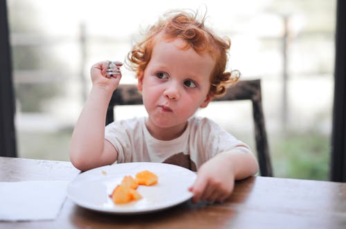 A Young Kid in White Shirt Eating Food