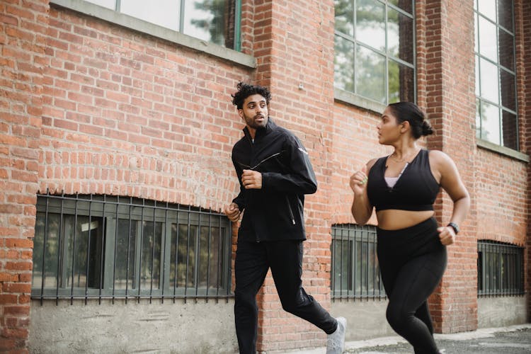 A Man And Woman Running On The Street While Having Conversation