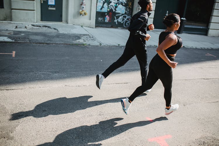 Man And Woman Jogging Together Along City Street