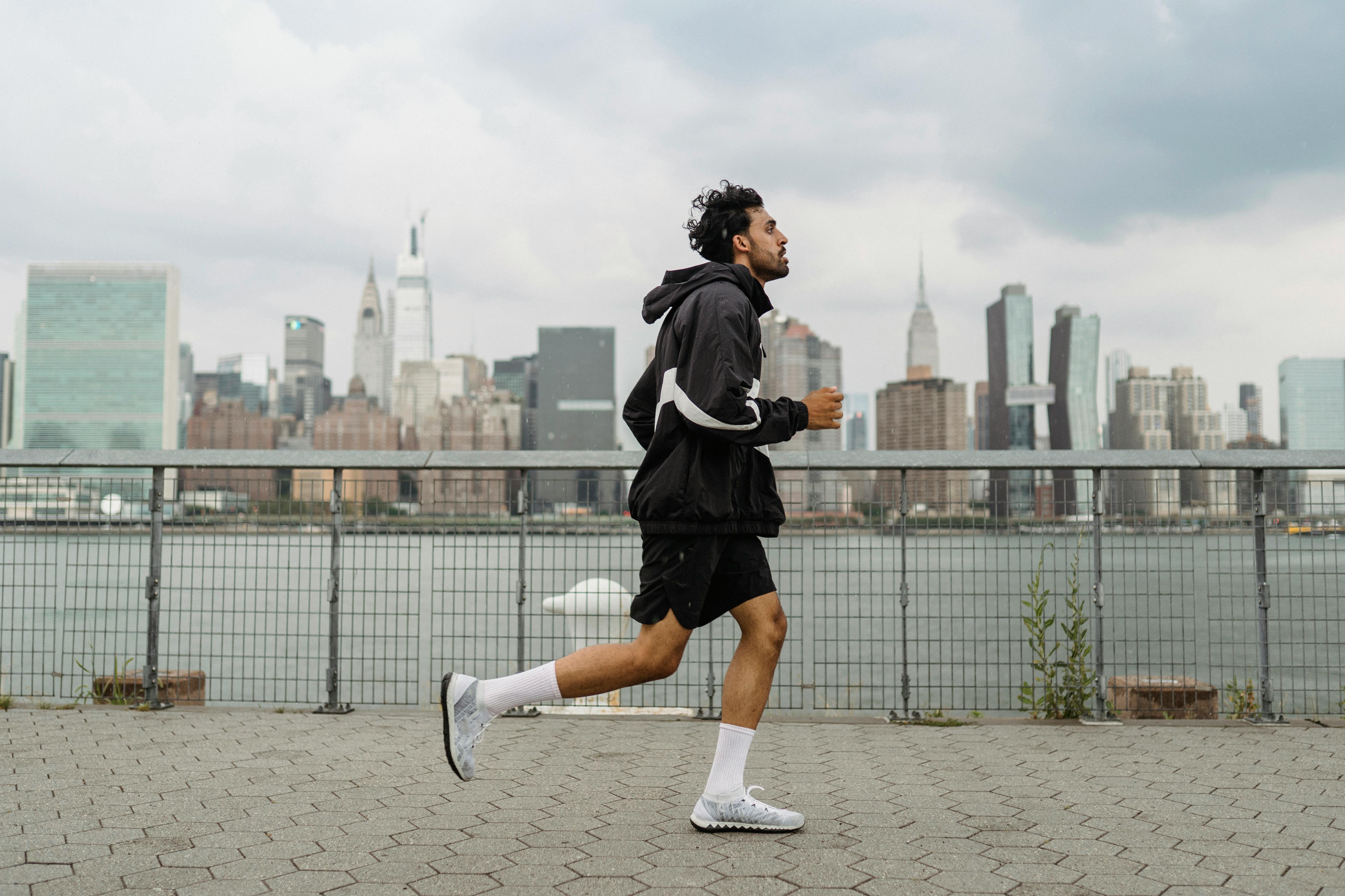 man wearing jacket and black shorts running in the city