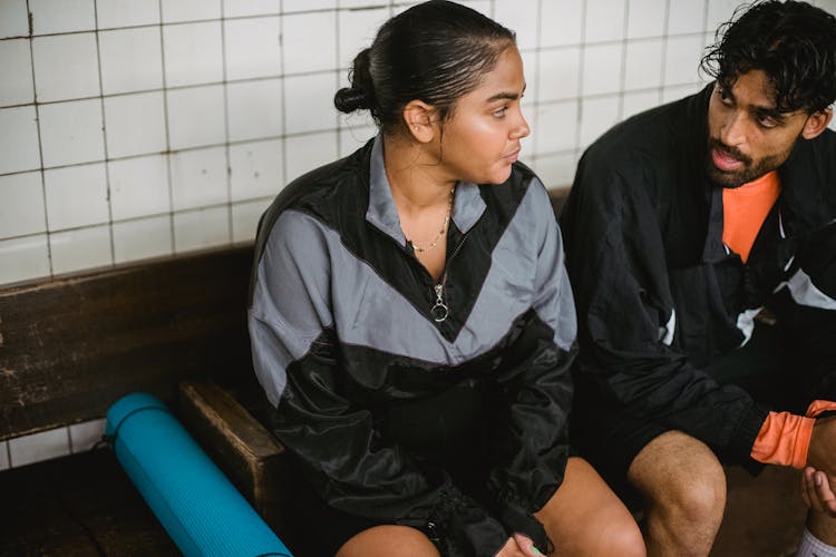 Couple Sitting On Bench Relaxing After Workout