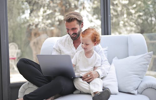 Free Smiling Dad and Son Using a Laptop Together Stock Photo