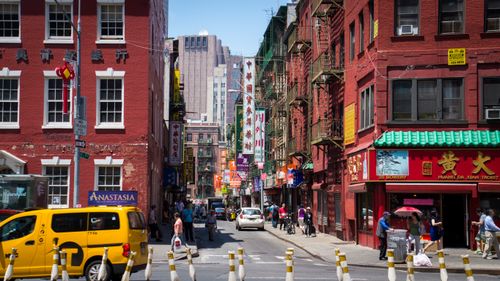 Free Busy daytime street scene in Chinatown, New York City with pedestrians, shops, and taxis. Stock Photo