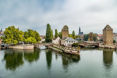 Free A picturesque scene of Strasbourg's historic buildings with reflection in the river under a blue sky. Stock Photo