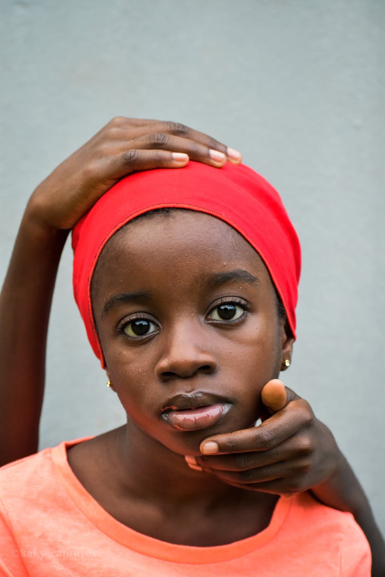 A Young Girl Wearing Headscarf While Someone Is Holding Her Head