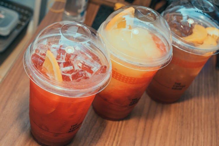 Cold Orange Drinks In Clear Plastic Cups