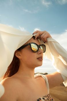 一位戴着墨镜和头巾的时尚女士，在户外捕捉着阳光明媚的优雅时刻