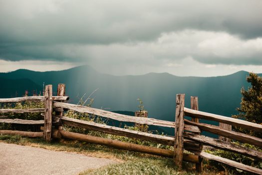 Wooden fence overlooking the Blue Ridge Mountains under an overcast sky. Tranquil summer scene.