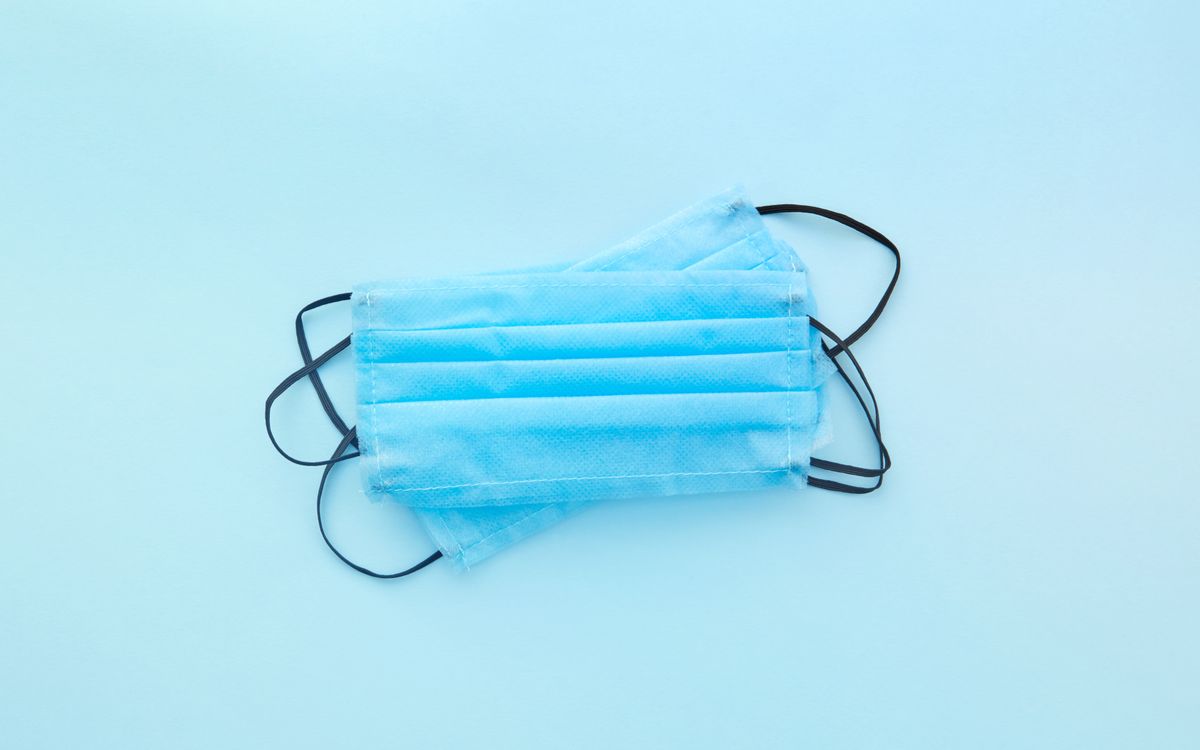 Close-up of blue disposable face masks on a light background with copy space.