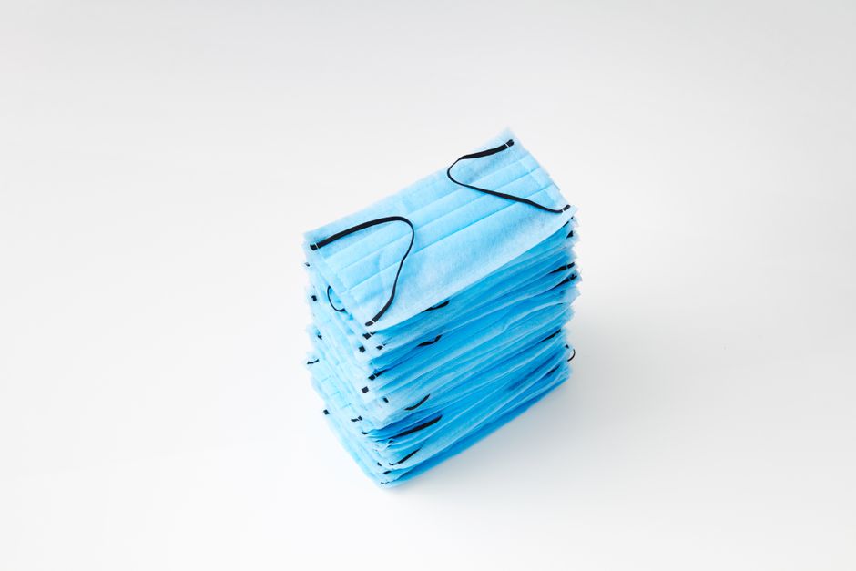 Una pila ordenada de mascarillas azules sobre un fondo blanco limpio, enfatizando la higiene y la protección.