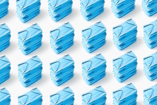 Multiple stacks of blue medical face masks arranged on a white background, emphasizing cleanliness and healthcare.