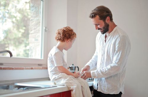 Free A loving father and son sharing a moment sitting by the kitchen sink. Stock Photo
