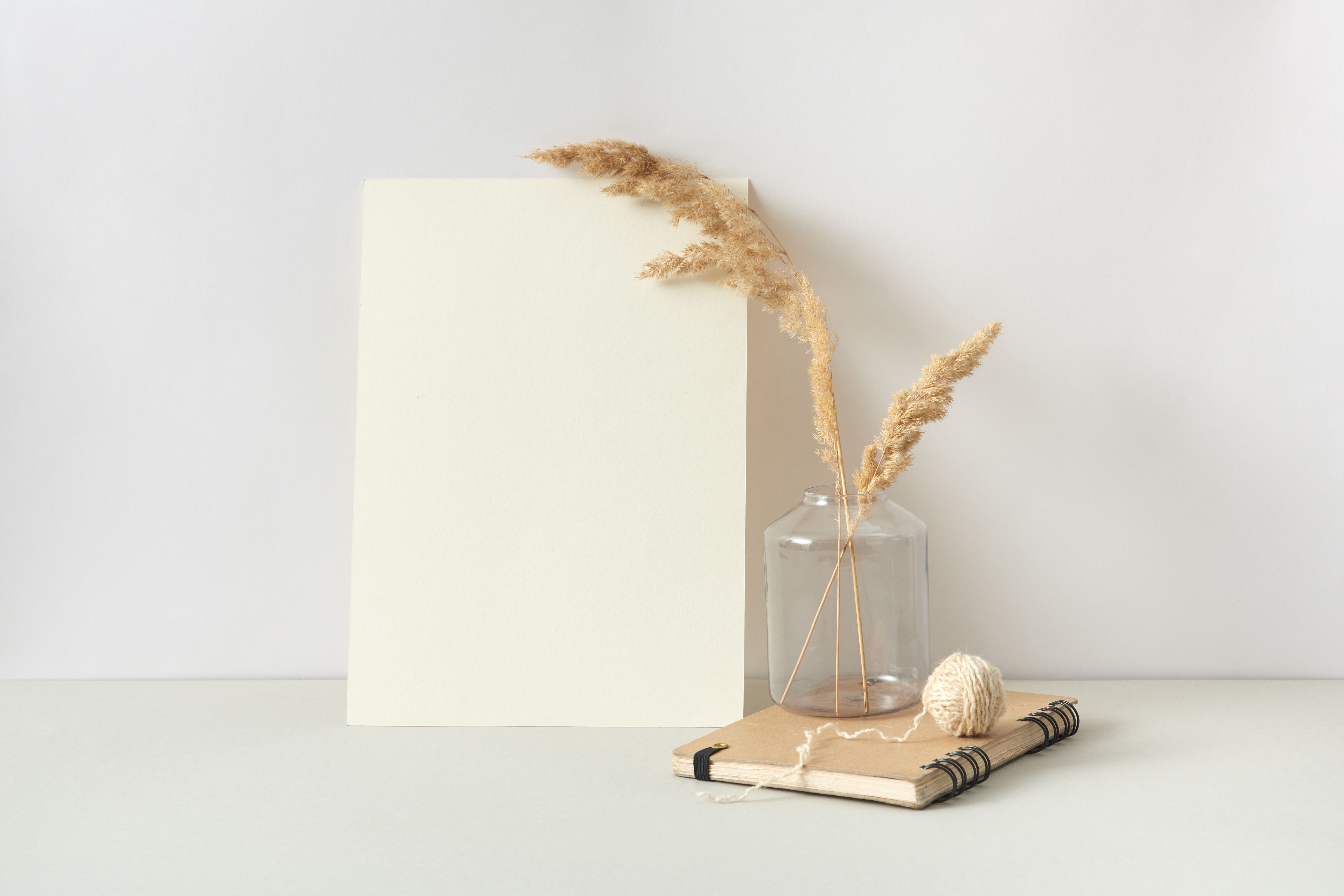 Elegant minimalist decor featuring dried grass in a vase beside a notebook and yarn ball.