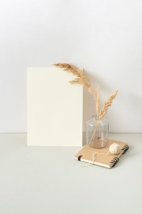 Free A minimalist still life photo featuring dry grass in a vase, a blank board, and a notebook on a neutral background. Stock Photo