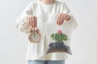 Woman Holding a Clock and a Plant in Plastic Bag 