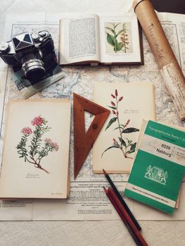 Flat lay of vintage camera, maps, and botanical prints on a desk.. flat, vintage, camera