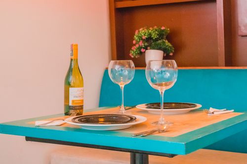 Free Charming dining setup with wine and glasses on a teal table, perfect for a romantic dinner. Stock Photo