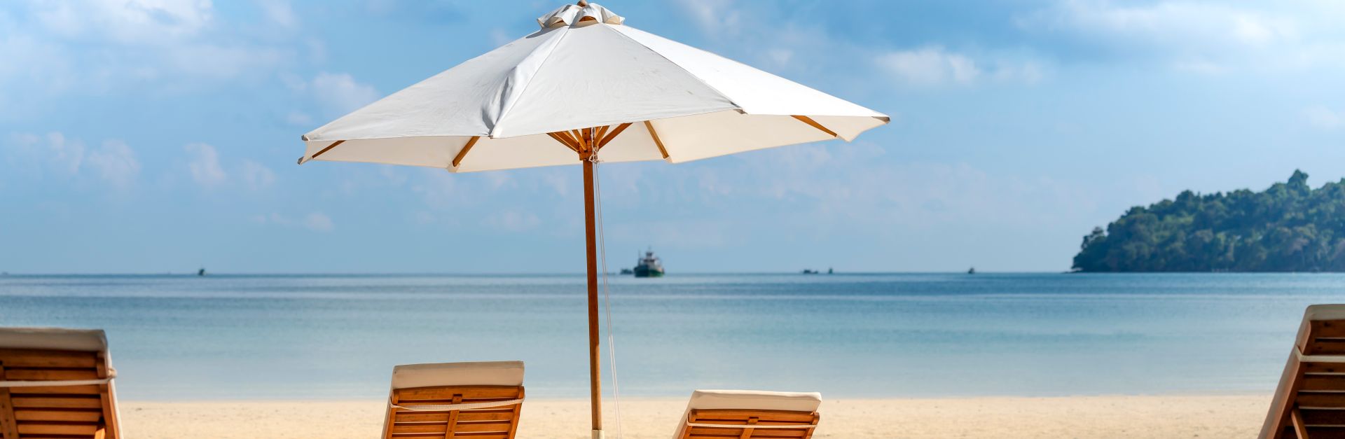 Relax on a serene tropical beach with wooden chairs and umbrellas, perfect for a summer retreat.