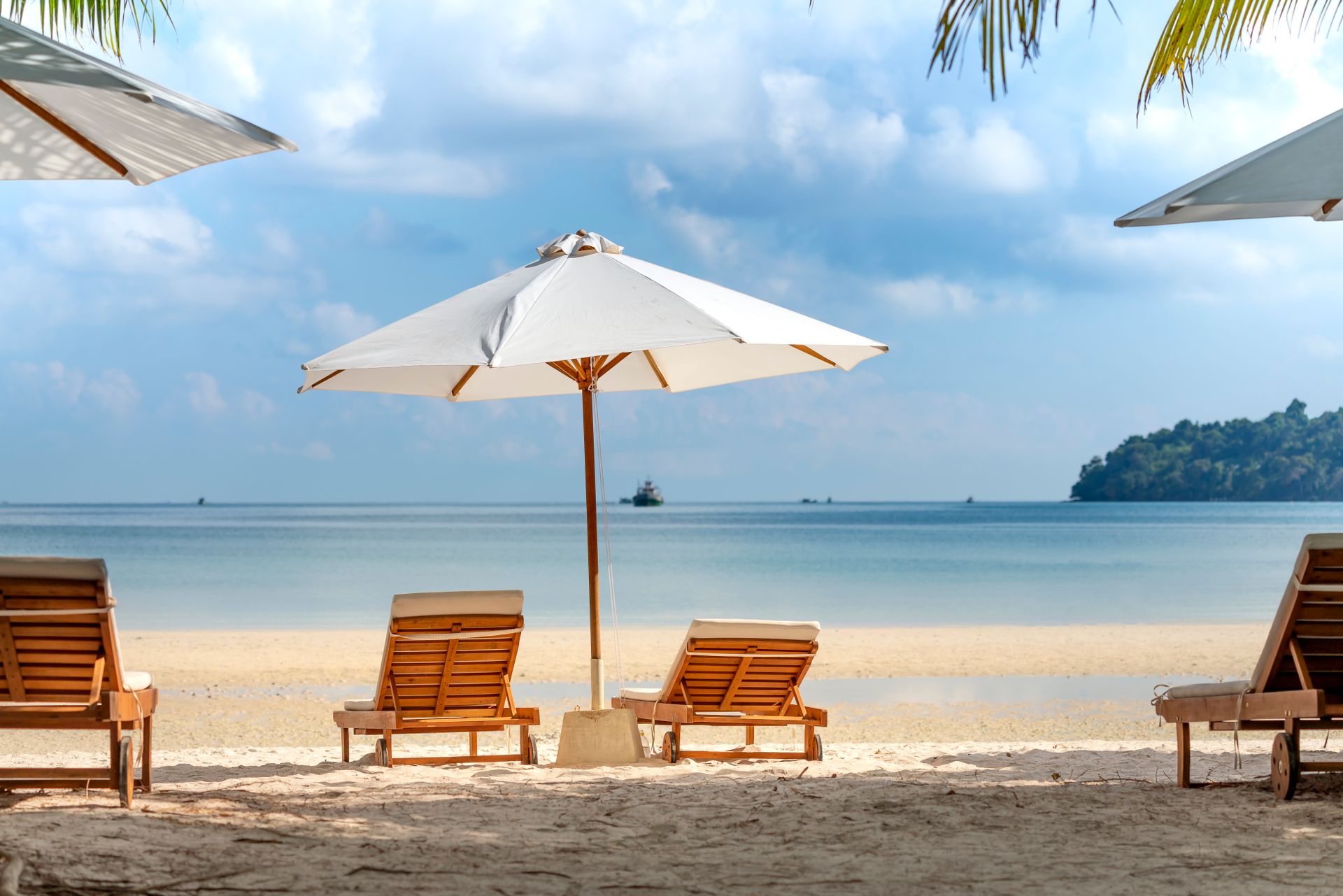 Relax on a serene tropical beach with wooden chairs and umbrellas, perfect for a summer retreat.