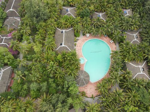 Free Breathtaking drone view of villas and swimming pool surrounded by lush palm trees in tropical resort on sunny day Stock Photo