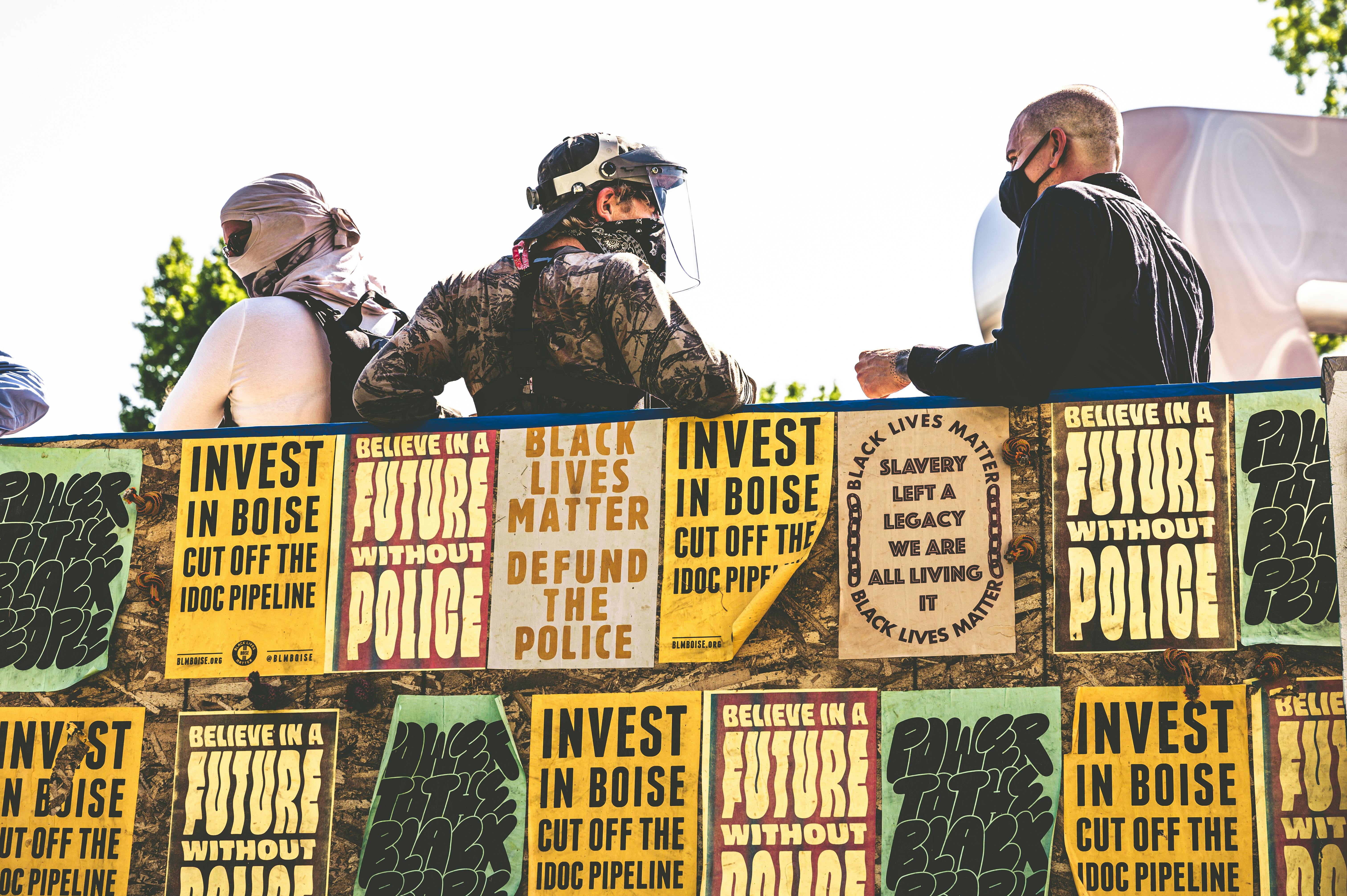 people in protective masks standing behind fence in posters