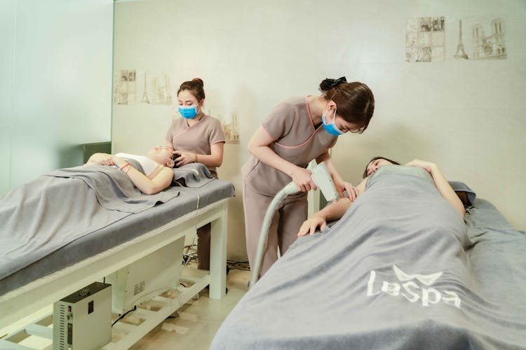 Women Wearing Face Mask Serving Treatment To Their Clients