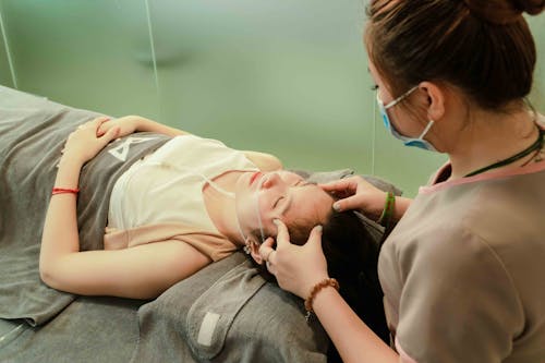 Free A Woman Lying Down while Having Her Head Massage by a Therapist Stock Photo