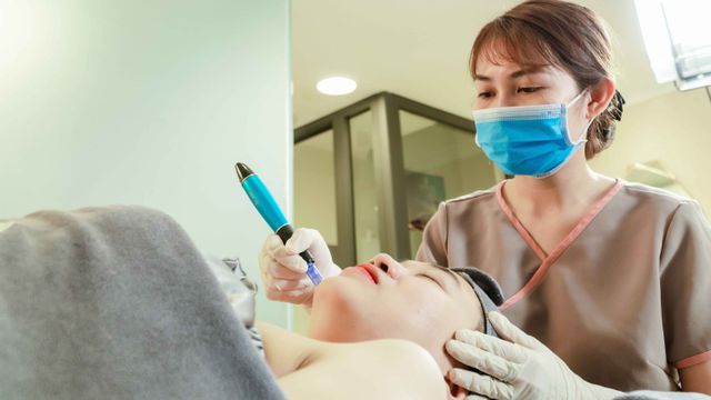 Profissional de estética em clínica especializada segurando equipamento estéril para tratamento de microneedling facial.