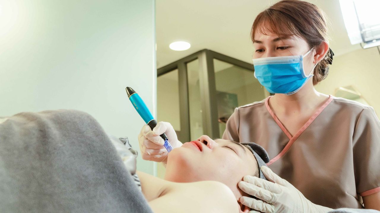 Profissional de estética em clínica especializada segurando equipamento estéril para tratamento de microneedling facial.