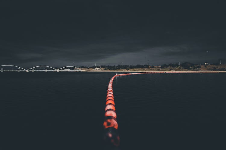 Bridge Over Calm Lake With Illuminated Buoy Line