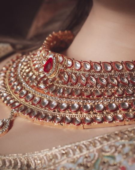 Layered kundan bridal necklace with a ruby-pink centre stone, worn by a bride