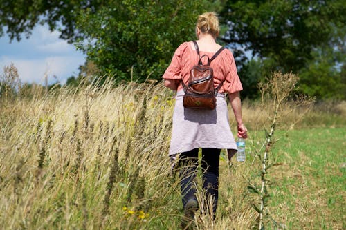 Woman in Pink Shirt Walking on Grass Field