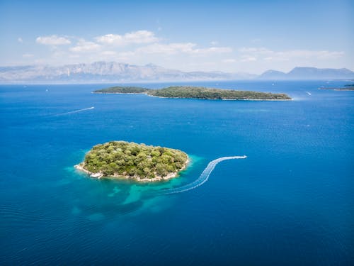 Amazing aerial view of boats floating in turquoise sea near islands with lush green vegetation on sunny day