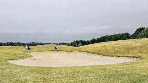 Person Walking on Green Grass Golf Course