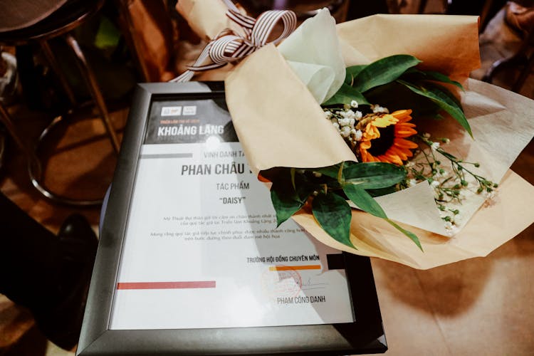 Bouquet Of Flowers Wrapped In Paper And An Information Plate 