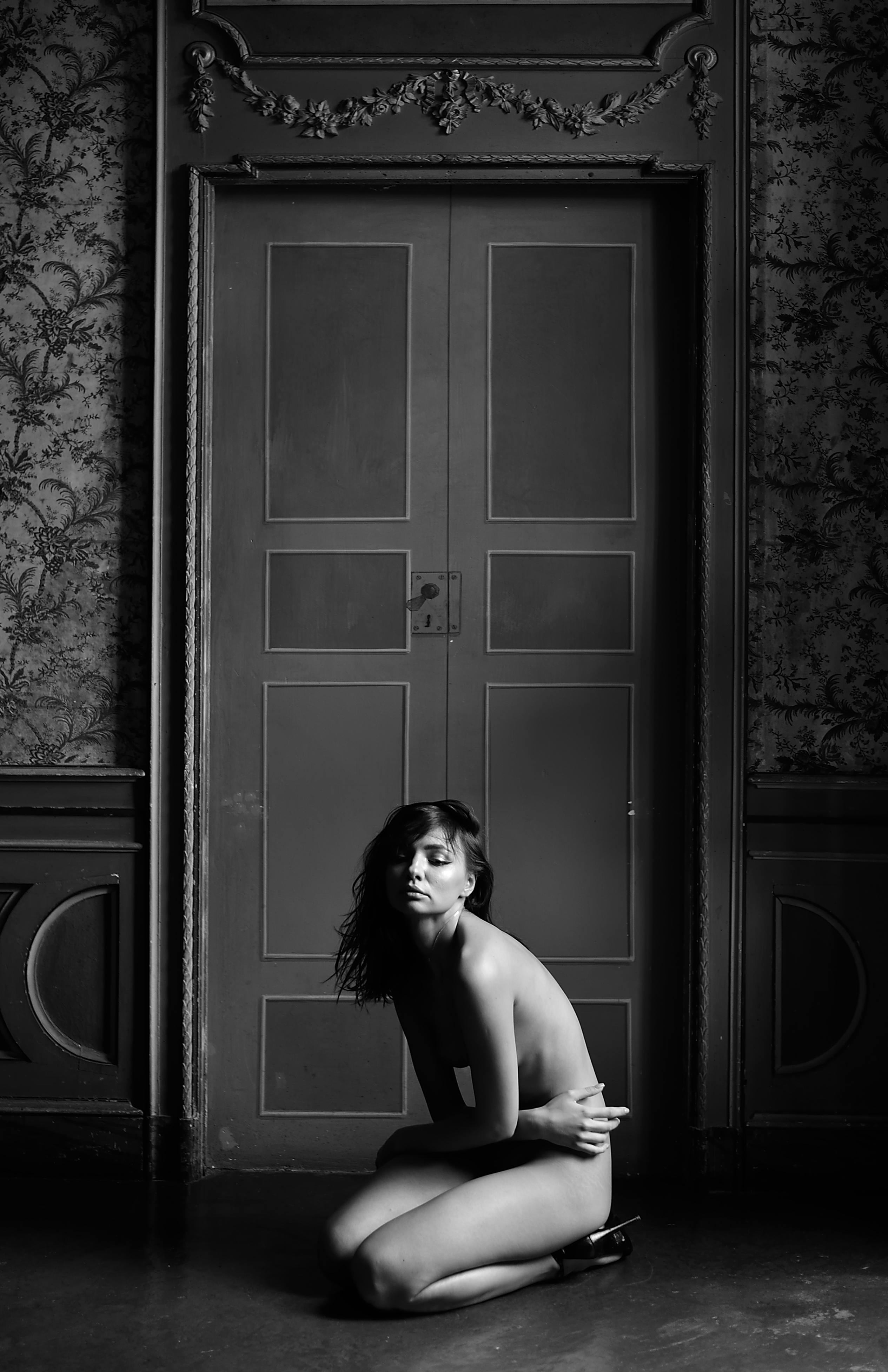 undressed woman sitting on knees in dark room