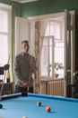 一名穿着条纹衬衫的男子，在时髦公寓休息室的台球桌旁沉思