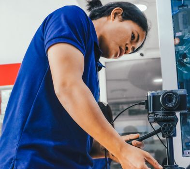 A focused young adult setting up a camera on a tripod indoors, symbolizing modern technology and creativity.