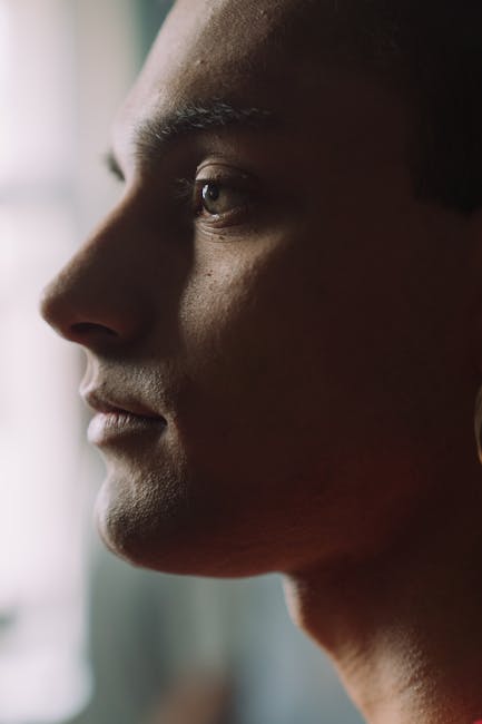 Close-up profile portrait of a man with a serene expression in gentle lighting.