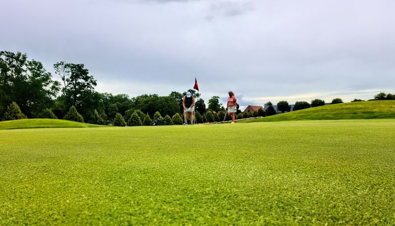 Players walking a green golf fairway together on a sunny day